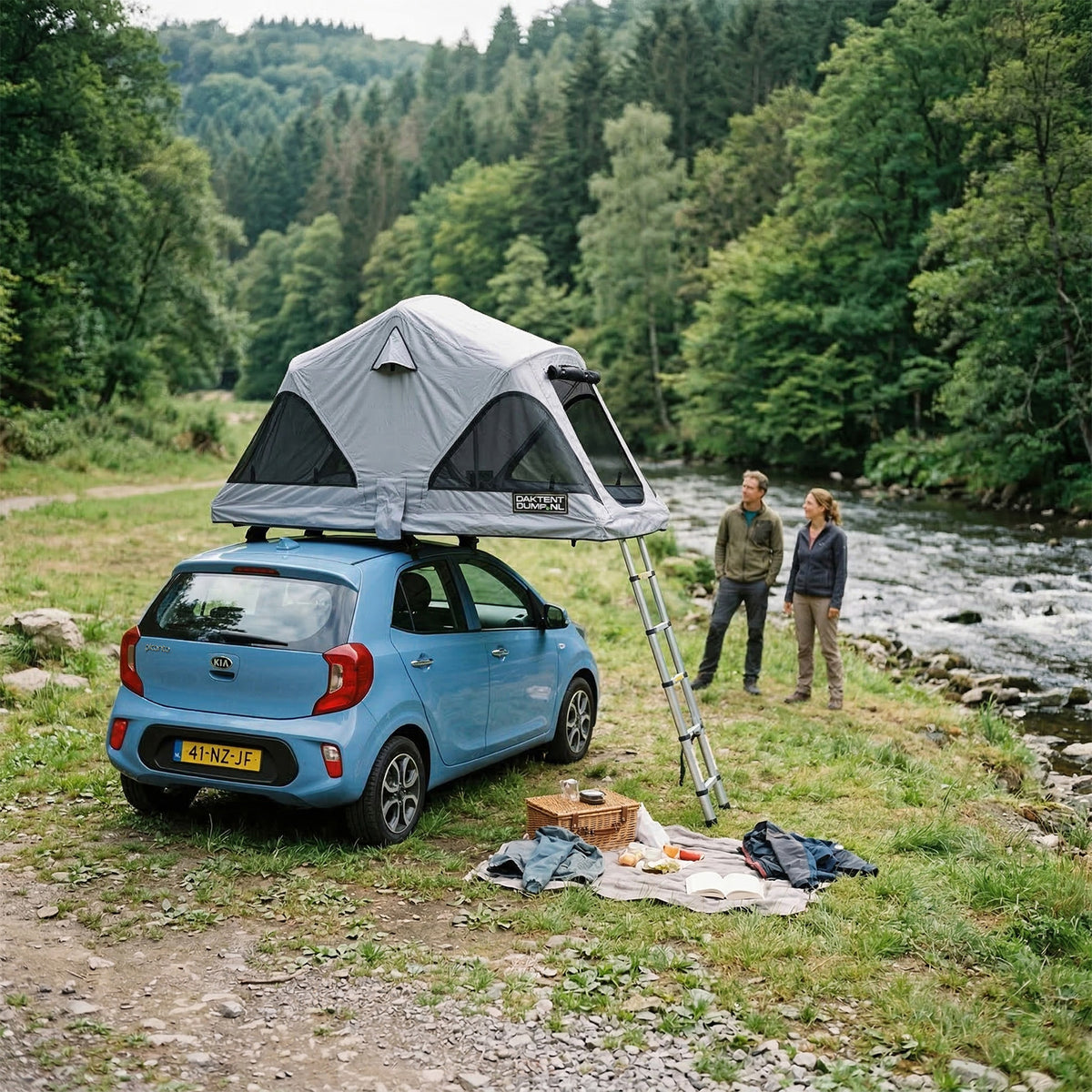 Compacte auto met daktent naast een rivier